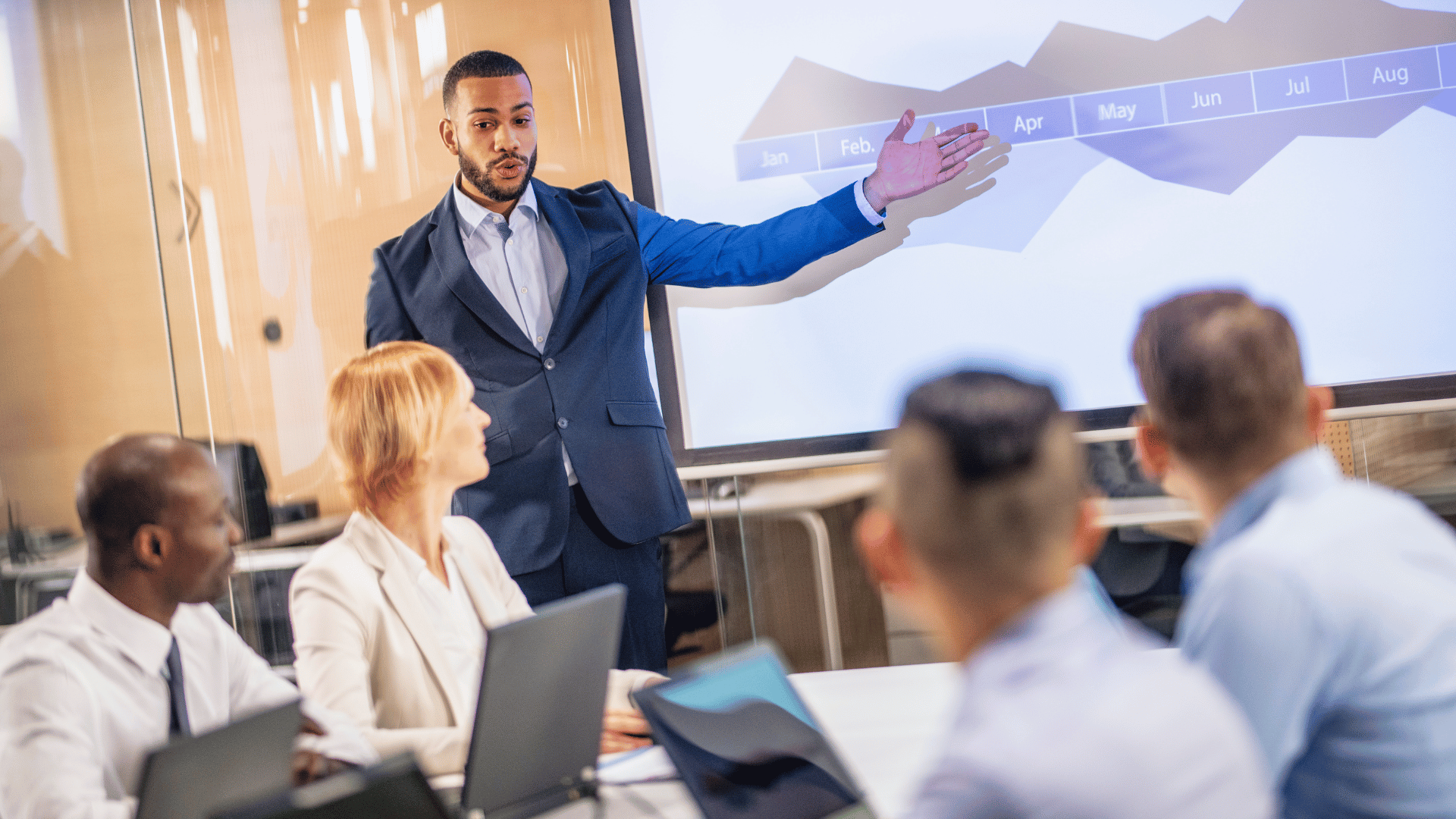 Businessman presenting a projection of report in a conference room to fellow Board members.