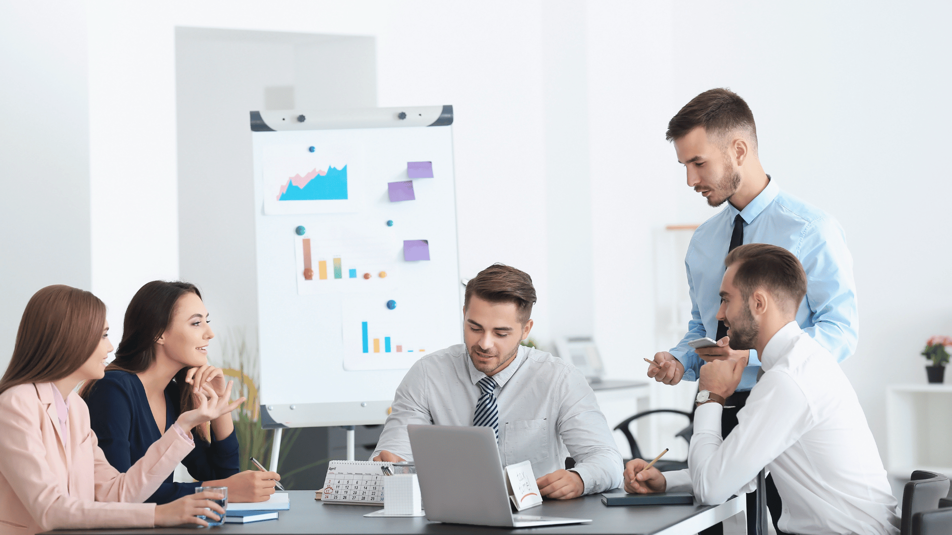 Five project management team members in a boardroom reviewing the progress of a project with an Arizzon team member.